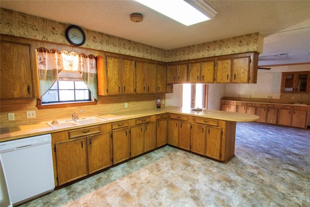 209 Simpson St, Schulenburg, TX 78956 - kitchen with white dishwasher, brown cabinetry, a sink, light countertops, and a textured ceiling