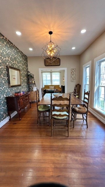 dining area featuring dark hardwood / wood-style flooring, a healthy amount of sunlight, and a notable chandelier