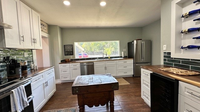 kitchen with white cabinetry, wine cooler, dark hardwood / wood-style flooring, backsplash, and appliances with stainless steel finishes