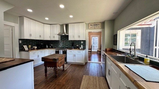 kitchen with white cabinetry, sink, dark wood-type flooring, wall chimney range hood, and stainless steel range oven