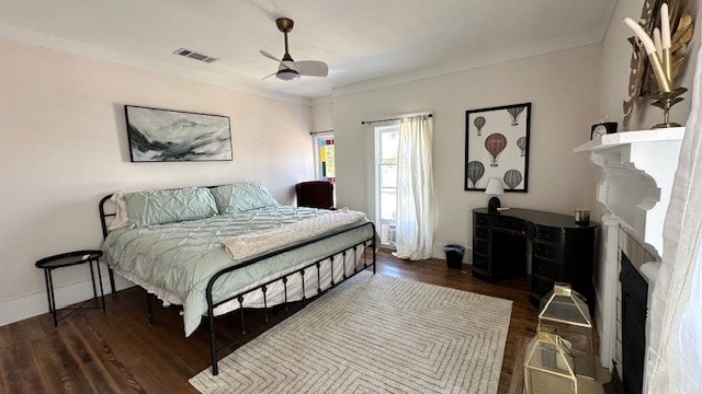 bedroom featuring ceiling fan, dark hardwood / wood-style floors, crown molding, and a fireplace