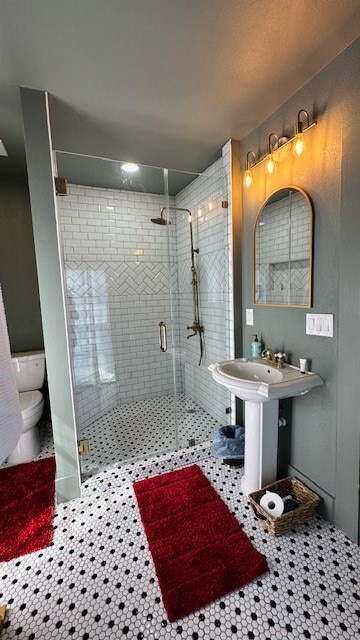 bathroom featuring tile patterned floors, toilet, and a shower with door