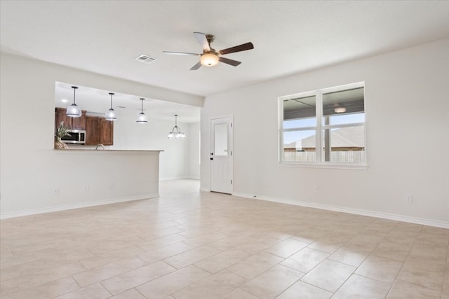 unfurnished living room with ceiling fan with notable chandelier and light tile patterned flooring