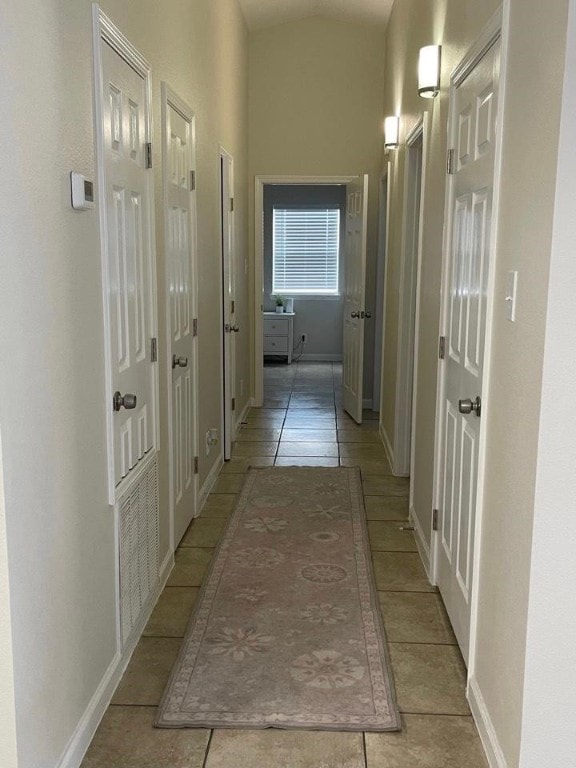 hallway with lofted ceiling and light tile patterned floors