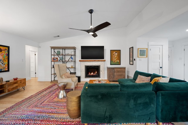 living room with lofted ceiling, ceiling fan, a fireplace with flush hearth, visible vents, and light wood-style floors