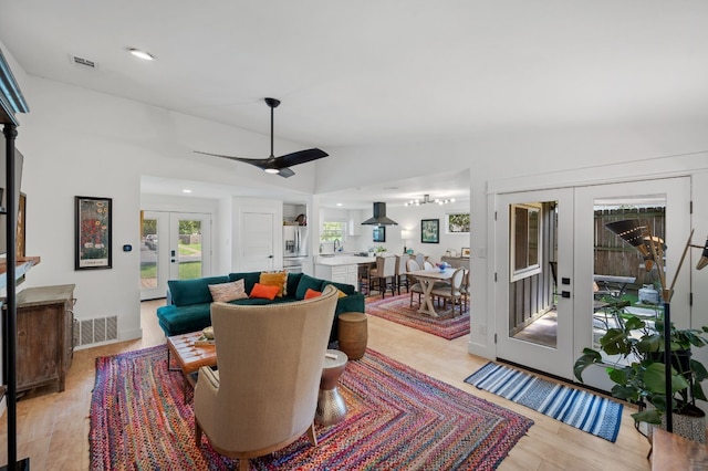 living room featuring ceiling fan, lofted ceiling, sink, french doors, and light wood-type flooring