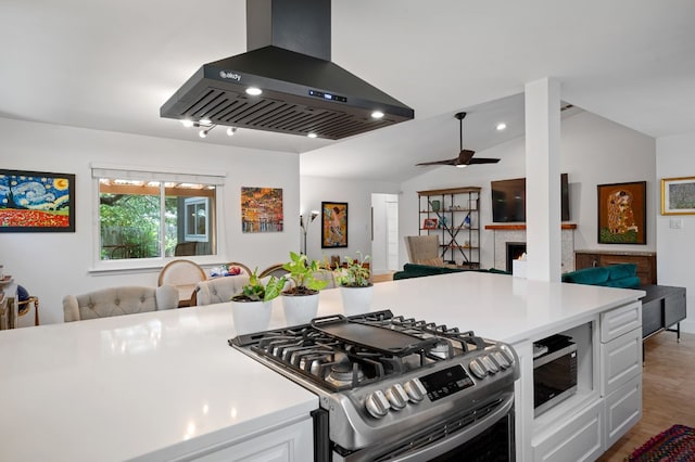 kitchen featuring white cabinets, open floor plan, island exhaust hood, light countertops, and stainless steel range with gas stovetop