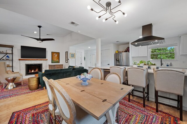 dining area featuring ceiling fan with notable chandelier, light hardwood / wood-style flooring, and lofted ceiling