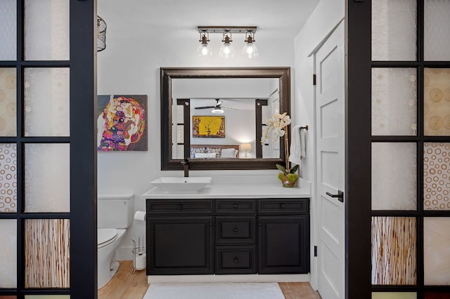 bathroom with toilet, wood finished floors, and vanity