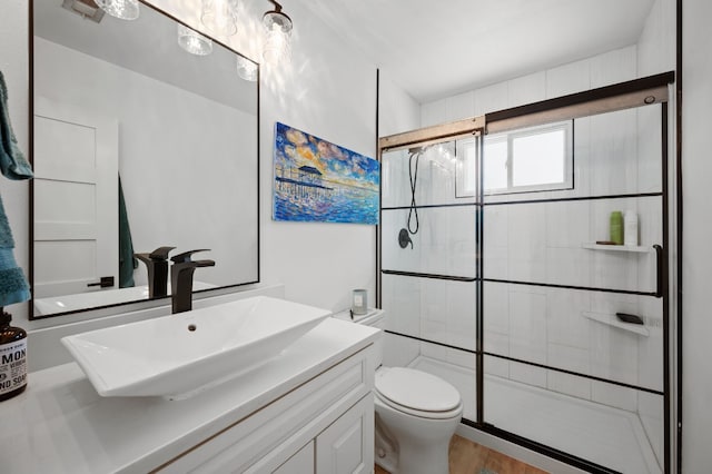 bathroom with walk in shower, wood-type flooring, vanity, and toilet