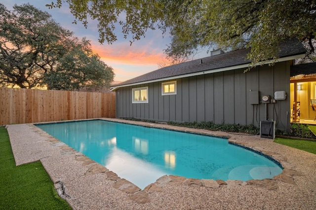 pool at dusk featuring a fenced in pool and a fenced backyard