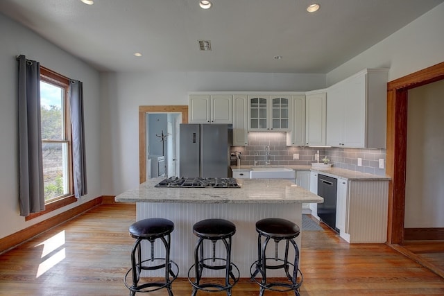 kitchen with light hardwood / wood-style floors, a kitchen island, sink, white cabinetry, and appliances with stainless steel finishes