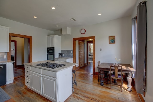 kitchen with white cabinetry, decorative backsplash, and black appliances