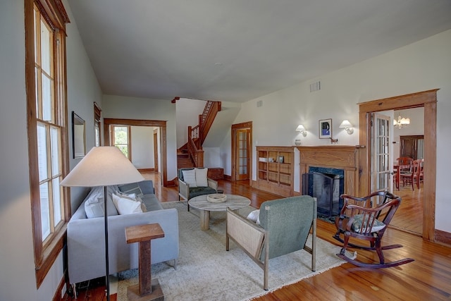 living room with a high end fireplace, an inviting chandelier, and light hardwood / wood-style floors