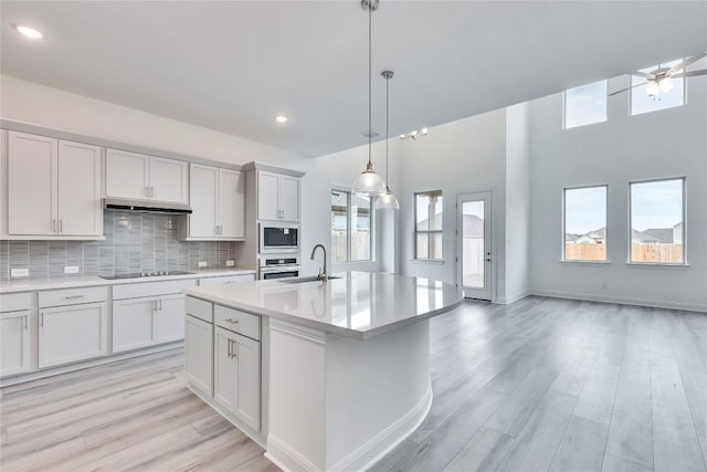 kitchen featuring decorative light fixtures, tasteful backsplash, light countertops, a sink, and built in microwave