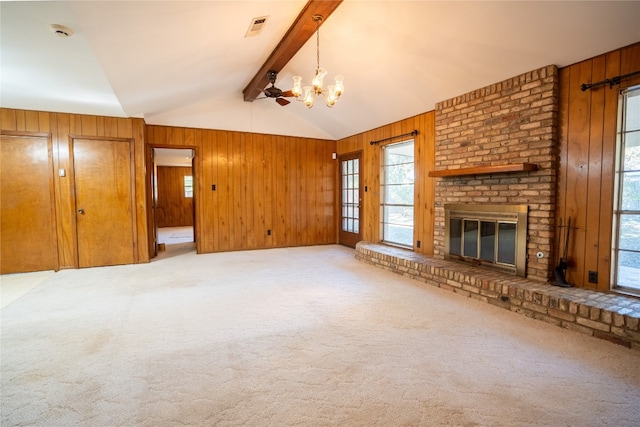 unfurnished living room featuring a brick fireplace, carpet floors, lofted ceiling with beams, and wood walls