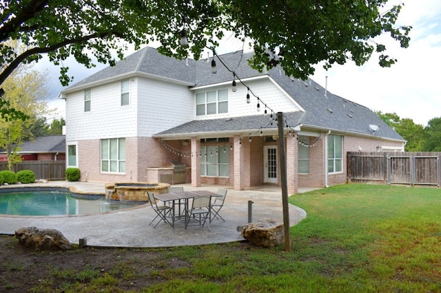 rear view of house featuring a yard, a patio area, and a pool with hot tub