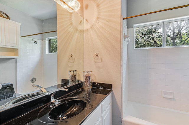 bathroom with vanity, a wealth of natural light, and tiled shower / bath