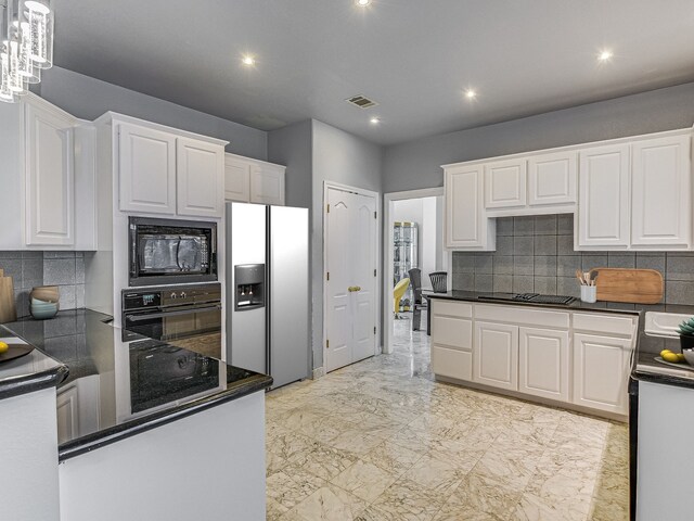 kitchen with hanging light fixtures, a notable chandelier, black appliances, tasteful backsplash, and white cabinetry