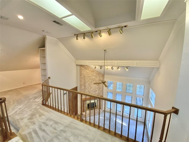 hallway featuring ornamental molding, carpet flooring, vaulted ceiling, and track lighting