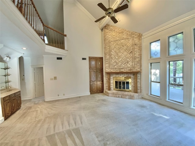 unfurnished living room with a fireplace, ornamental molding, light colored carpet, and high vaulted ceiling