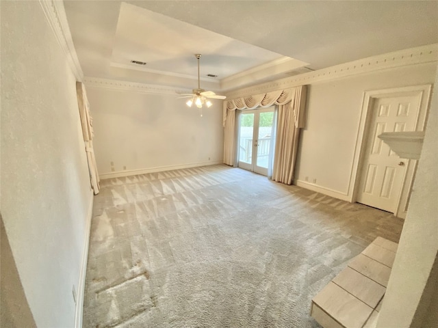 unfurnished room featuring ceiling fan, a raised ceiling, ornamental molding, french doors, and light carpet