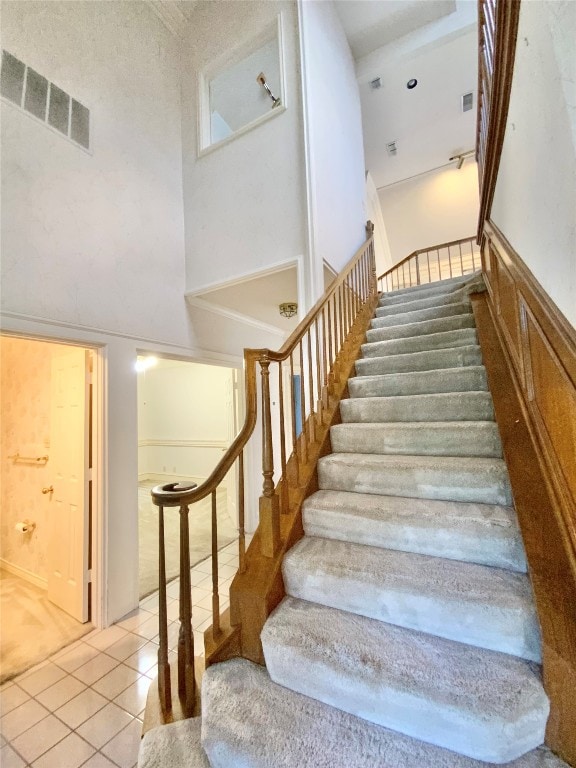 stairway featuring a towering ceiling and tile patterned floors