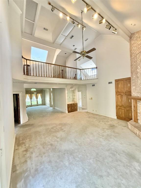 7011 Quill Leaf Cv, Austin, TX 78750 - unfurnished living room with rail lighting, high vaulted ceiling, carpet flooring, and a ceiling fan