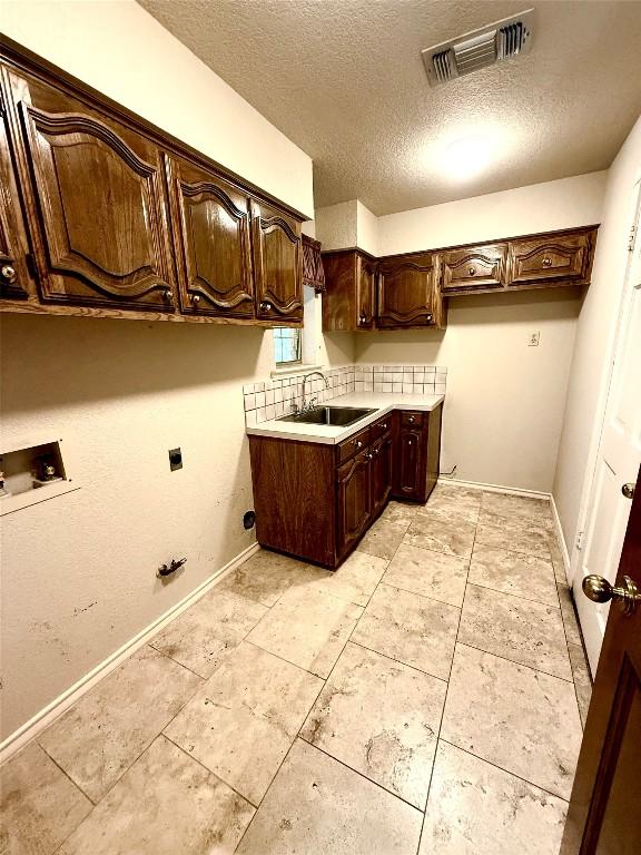 7011 Quill Leaf Cv, Austin, TX 78750 - washroom with cabinet space, washer hookup, a textured ceiling, electric dryer hookup, and light tile patterned floors