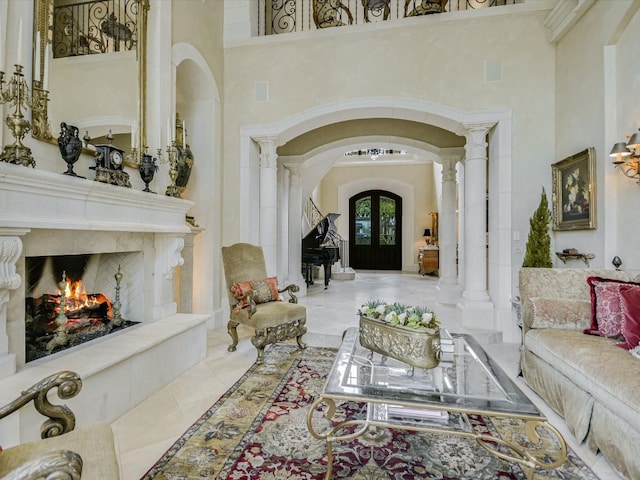 hallway with decorative columns, a towering ceiling, and french doors