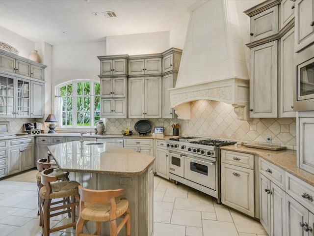 kitchen featuring appliances with stainless steel finishes, custom range hood, a kitchen breakfast bar, and tasteful backsplash