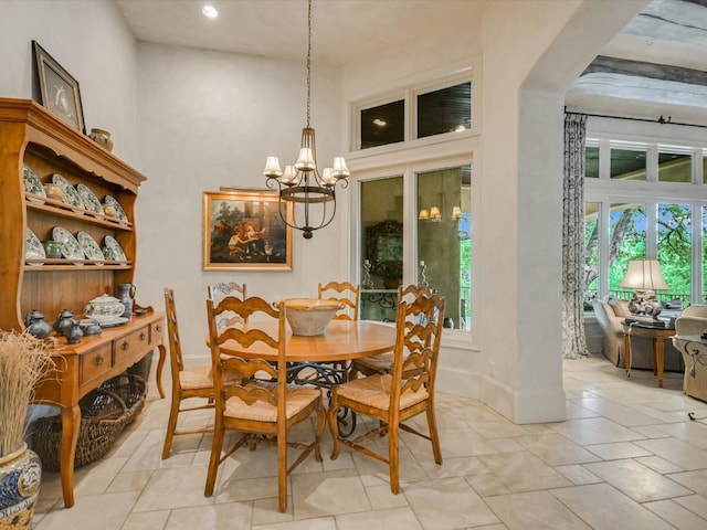 dining space featuring a towering ceiling and a chandelier