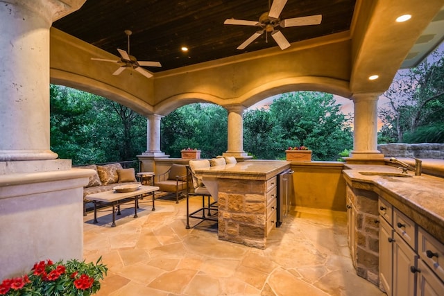 patio terrace at dusk featuring a wet bar and ceiling fan