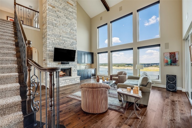 living room with a stone fireplace, dark wood-type flooring, high vaulted ceiling, and a wealth of natural light