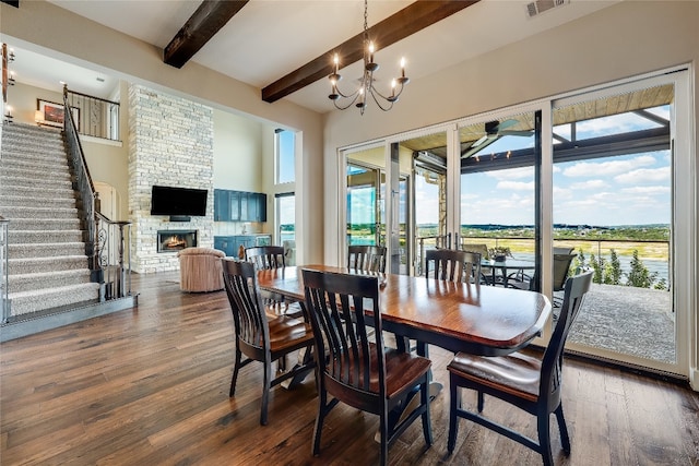 dining area with dark hardwood / wood-style flooring, beamed ceiling, plenty of natural light, and a stone fireplace