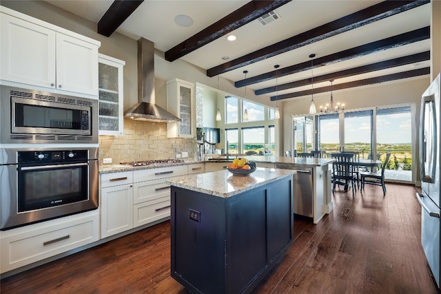 kitchen with beamed ceiling, kitchen peninsula, a kitchen island, wall chimney exhaust hood, and appliances with stainless steel finishes