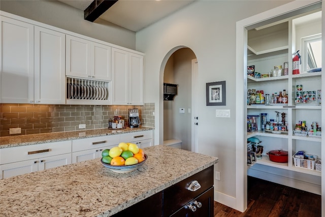 kitchen with light stone countertops, white cabinetry, dark hardwood / wood-style floors, and tasteful backsplash