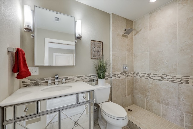 bathroom featuring vanity, a tile shower, and toilet