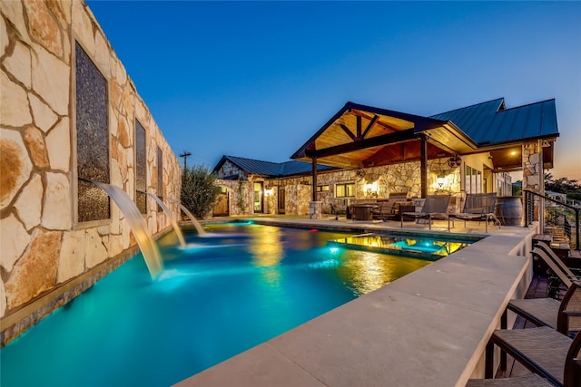 pool at dusk with pool water feature, a patio, ceiling fan, and outdoor lounge area