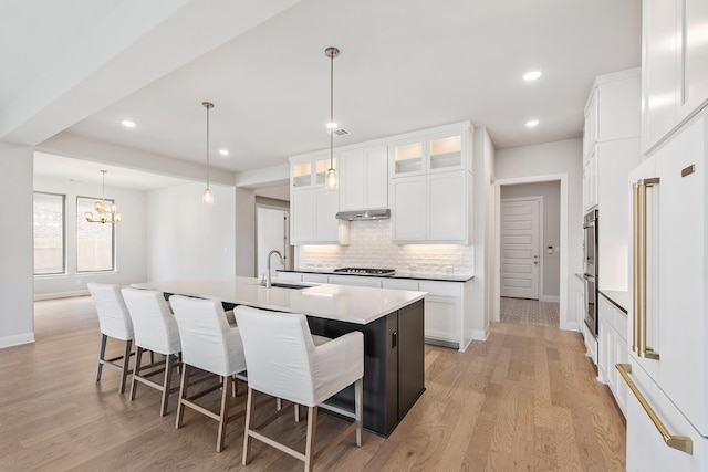 kitchen featuring sink, white cabinetry, a center island with sink, decorative backsplash, and stainless steel gas cooktop