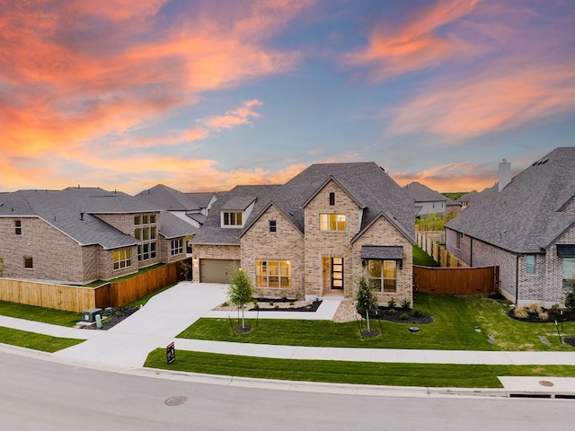 french country inspired facade featuring a garage and a yard