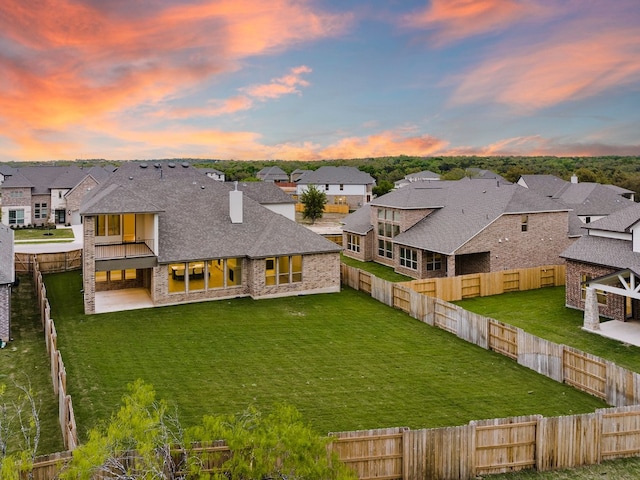 back house at dusk with a patio and a lawn