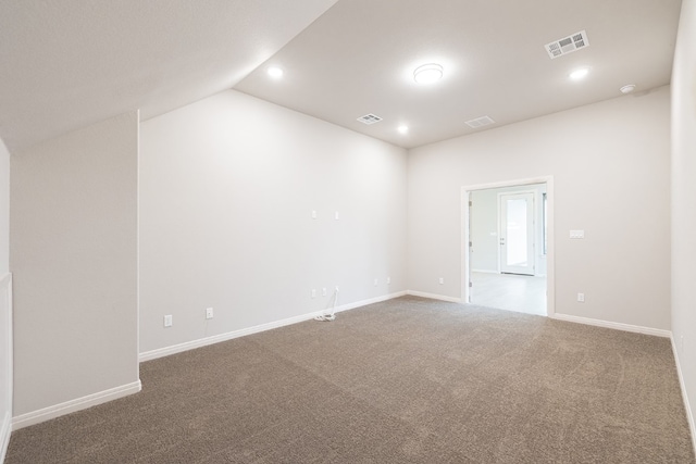 carpeted empty room featuring vaulted ceiling