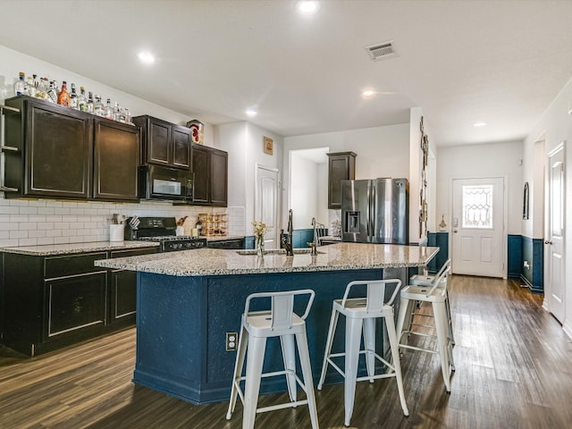 kitchen featuring a center island with sink, dark hardwood / wood-style floors, sink, and black appliances