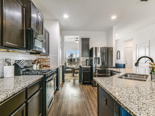 kitchen with dark hardwood / wood-style flooring, light stone counters, appliances with stainless steel finishes, and sink