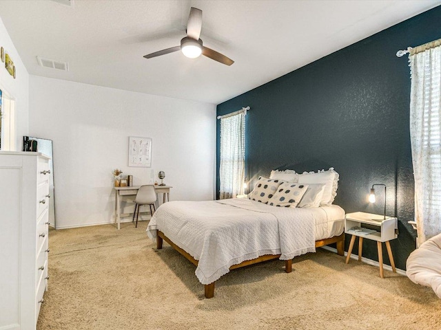 bedroom with visible vents, a ceiling fan, and light colored carpet
