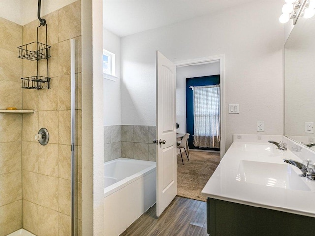 bathroom with wood finished floors, a garden tub, a stall shower, and a sink