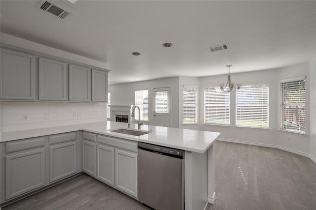 kitchen with sink, stainless steel dishwasher, tasteful backsplash, a notable chandelier, and kitchen peninsula