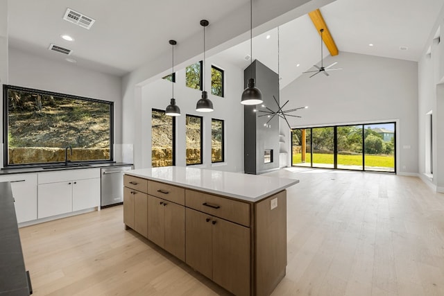 kitchen with decorative light fixtures, beam ceiling, a healthy amount of sunlight, and white cabinetry