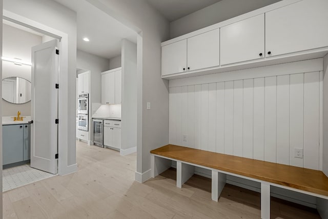 mudroom with light hardwood / wood-style flooring and wine cooler